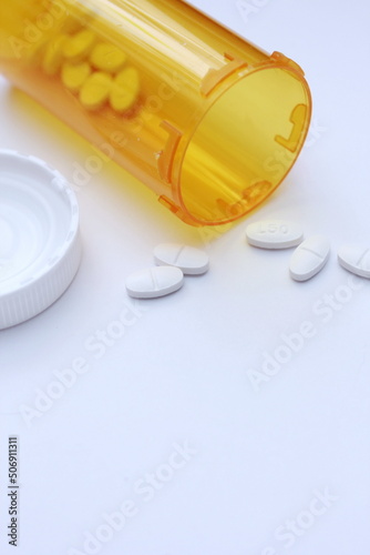 Oval pills and orange pill bottles were spread out on the white tabletop.
