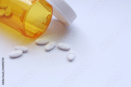 Oval pills and orange pill bottles were spread out on the white tabletop.