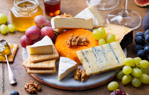 Assortment of cheese, crackers, grapes. Snack for wine. Marble cutting board. Wooden background. Close up.