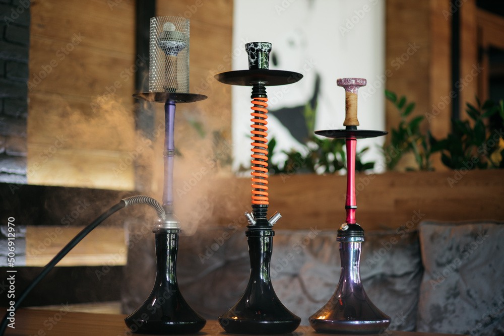 Hookah smoking at a party concept. Hookah stands on a wooden table in a restaurant. Smoking concept. Hookah on the table. Smoking tobacco. Hookah smoking at a party concept. Hookah stands on a wooden table in a restaurant. Smoking concept. Hookah on the table. Smoking tobacco.