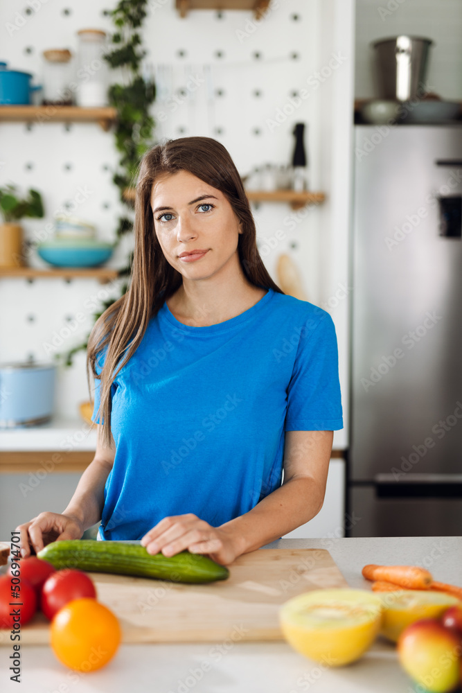 Young woman preparing salad in the kitchen and looking at camera Young woman preparing salad in the kitchen and looking at camera
