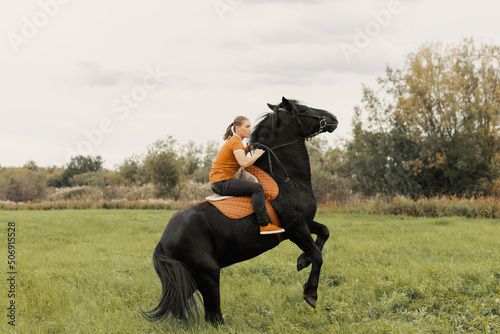 Rearing horse with rider upon back in meadow.