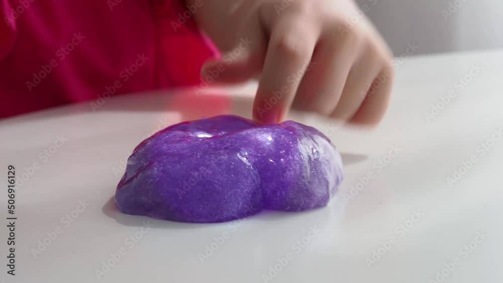 Play with texture slime, stretching the sticky substance. Child's hand of a child holds touches purple slime, squeezing it. Press your fingers on a liquid toy. 4K.