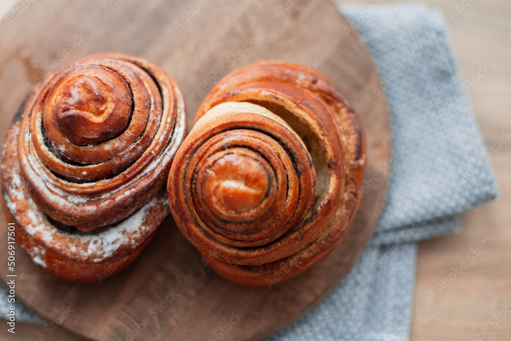 Delicious sweet buns lie on a wooden round board on the kitchen, top view. Baking Delicious sweet buns lie on a wooden round board on the kitchen, top view. Baking