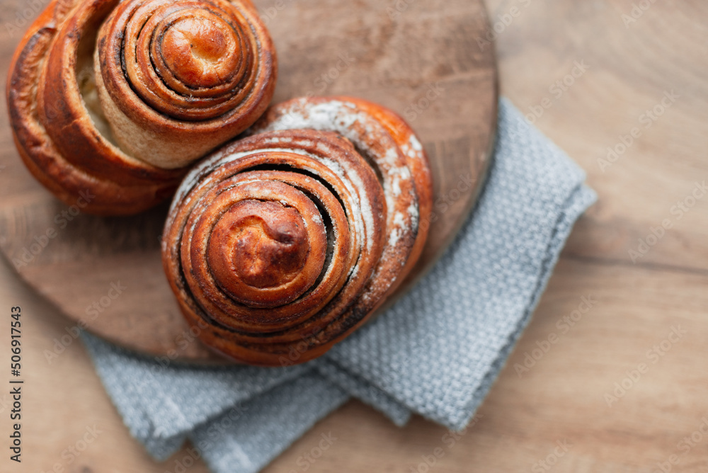 Delicious sweet flour pastries buns on a wooden board with a napkin fabric, top view Delicious sweet flour pastries buns on a wooden board with a napkin fabric, top view