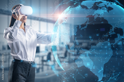 Cyberspace, metaverse and virtual reality concept with handsome young woman in VR headset projected virtual reality hologram with world map globe on abstract office background