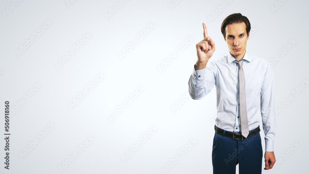 Young handsome man in shirt with raising up hand and forefinger isolated on abstract light background with empty place for your logo or text, mock up Young handsome man in shirt with raising up hand and forefinger isolated on abstract light background with empty place for your logo or text, mock up