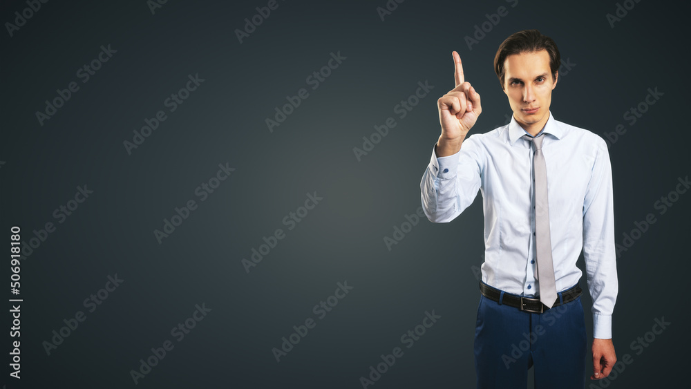 Young handsome man in shirt with raising up hand and forefinger isolated on abstract dark background with empty place for your logo or text, mock up Young handsome man in shirt with raising up hand and forefinger isolated on abstract dark background with empty place for your logo or text, mock up