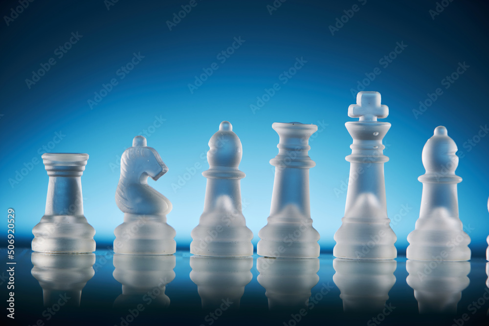 glass chess on the chess board against blue background glass chess on the chess board against blue background