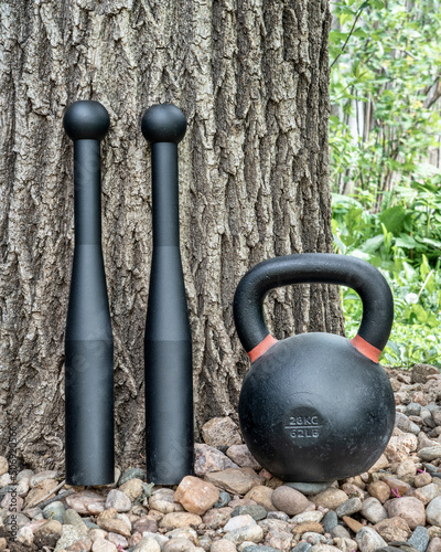 pair of steel clubs and kettlebell in backyard, functional fitness concept, heavy clubs are particularly valuable for grip strength, shoulder work, and rotational core power photo