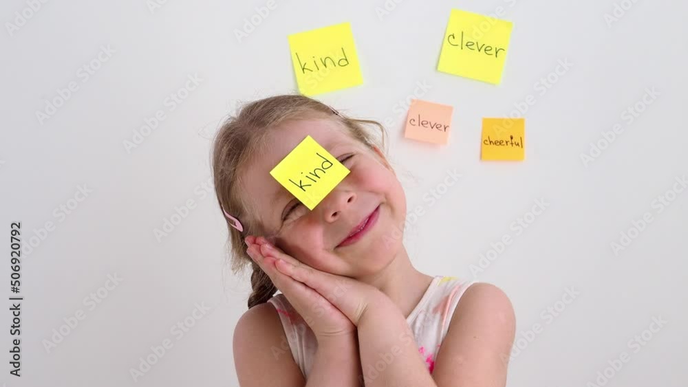 A small, sweet, kind girl with a sticker on her forehead. Put a label on a person. Characteristics of the child. Child psychology concept. 4k. Children's portrait of a girl. Text on stickers.