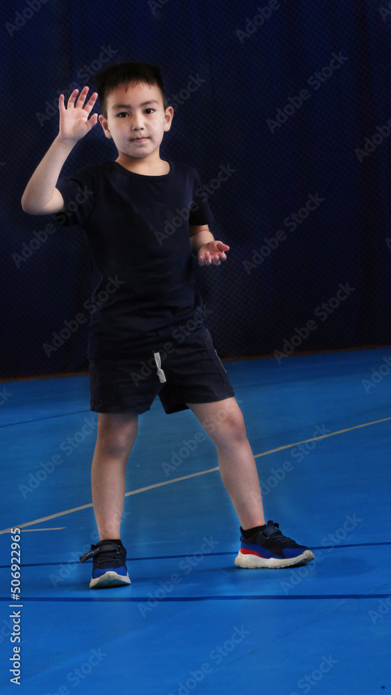Little boy model wearing sports tracksuit with sweatshirt and pants studio portrait isolated on blue background. Male child posing for camera with hands in pocket. selective focus Little boy model wearing sports tracksuit with sweatshirt and pants studio portrait isolated on blue background. Male child posing for camera with hands in pocket. selective focus