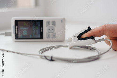 Man using finger pulse oximeter, healthcare monitoring concept. Pulse oximeter on a white background photo