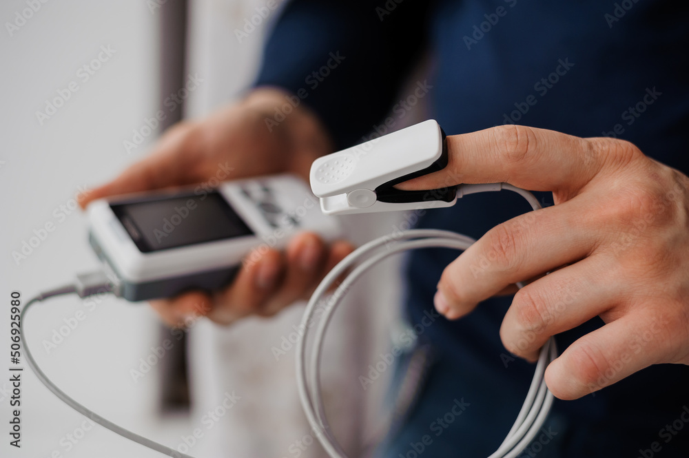 Man using finger pulse oximeter, healthcare monitoring concept. Pulse oximeter on a white background