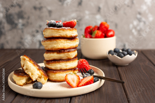 Fresh pancakes laid out in a stack, decorated with fresh berries, sprinkled with powdered sugar, beautiful serving