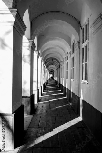Black and white image of Canon's Corridor in Oradea, Romania, constructed between 1758 and 1875 as a clergy house, the architectural monument is 253 m long and it has 57 arcades.
