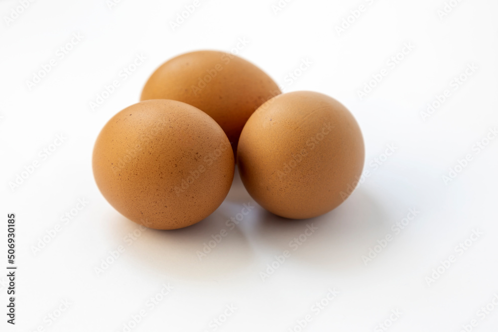 Chicken eggs on a white background, close up, three raw eggs. Chicken eggs on a white background, close up, three raw eggs.