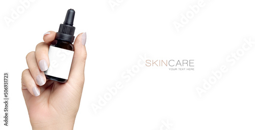 Female hand holding up a mock-up dropper bottle with empty label in a cosmetology and skincare concept. isolated on white with copy space