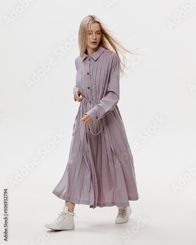 Studio photoshoot of a smiling young blond woman wearing casual clothing against a white background.  Natural makeup and hairstyle