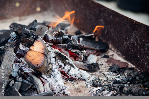 A brightly burning bonfire with a red flame made from wood in an outdoor grill.An adventurous lifestyle in travel. Active weekend recreation in the wild outdoors.