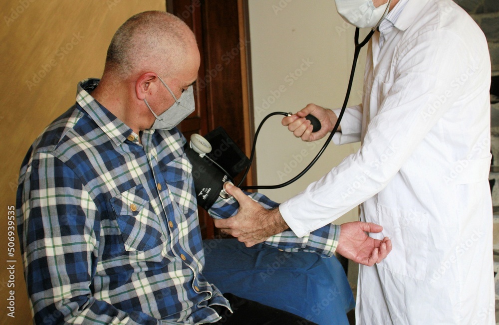 Médico accionando tensiómetro para medir presión arterial en paciente adulto - obrazy, fototapety, plakaty 