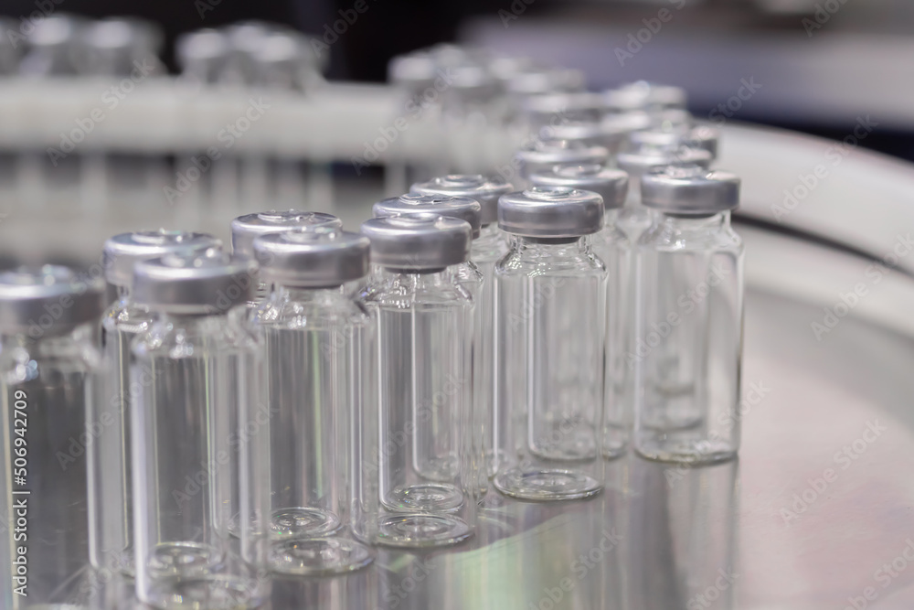 Conveyor belt with empty medical injection glass vials - pharmaceutical automatic production line. Pharmaceutical industry, manufacturing, medicine and automated pharma technology equipment concept Conveyor belt with empty medical injection glass vials - pharmaceutical automatic production line. Pharmaceutical industry, manufacturing, medicine and automated pharma technology equipment concept