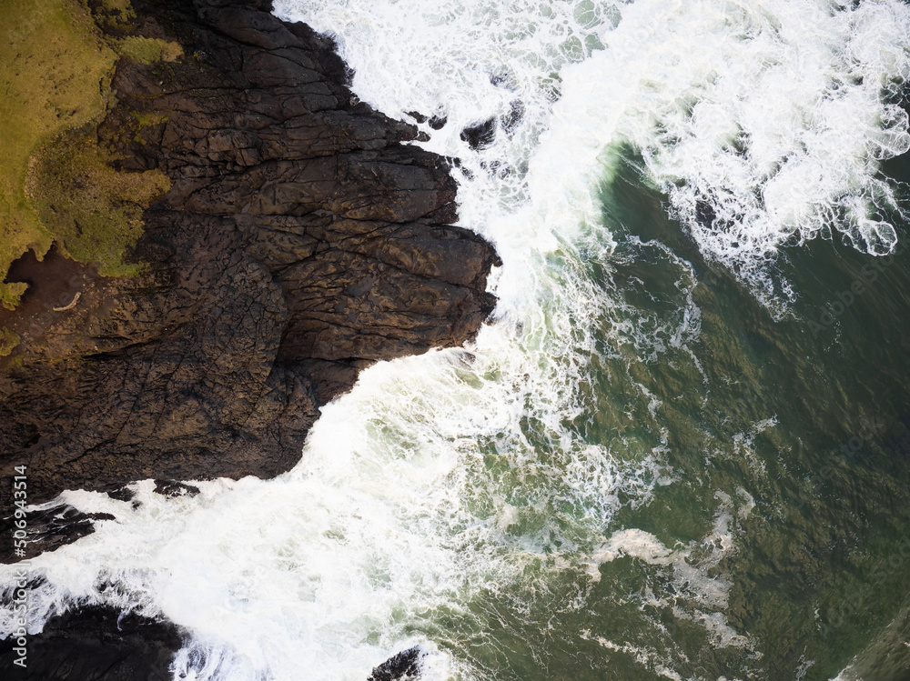 An aerial view of ocean waves crashing against a hilly shore. A beautiful piece of wild nature. Minimalism. Abstraction. Travel, tourism, postcard, banner. An aerial view of ocean waves crashing against a hilly shore. A beautiful piece of wild nature. Minimalism. Abstraction. Travel, tourism, postcard, banner.