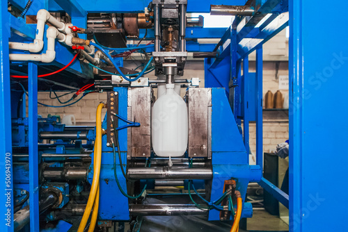Production of plastic canisters on an automatic conveyor. The mechanism heats the polyethylene and blows out the finished canister.