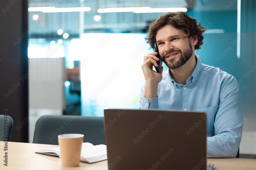Smiling man working and talking on cell phone at office Smiling man working and talking on cell phone at office