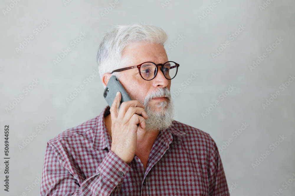man with gray hair is working in an office on a laptop and talking on the phone. an adult male director or businessman is negotiating on an online webcam. business and finance of a male lawyer or man with gray hair is working in an office on a laptop and talking on the phone. an adult male director or businessman is negotiating on an online webcam. business and finance of a male lawyer or