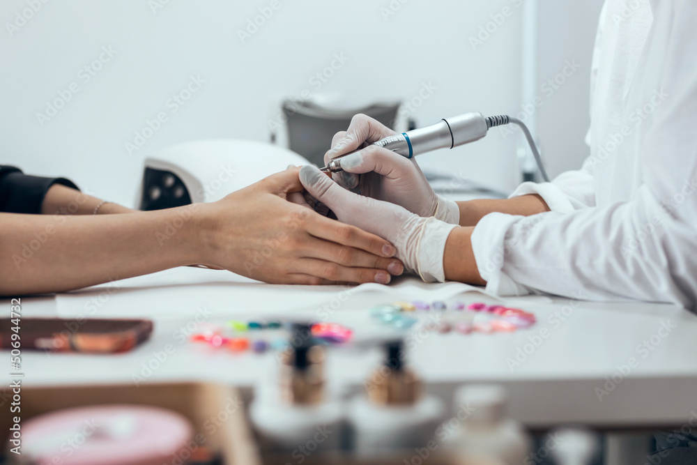 Fototapeta premium Young woman doing permanent manicure in salon. Beauty concept.