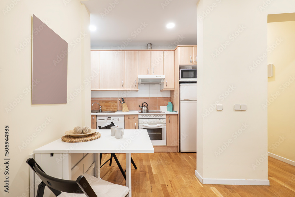 Fototapeta premium Apartment with open kitchen, living room with square white folding dining table and light wooden floor