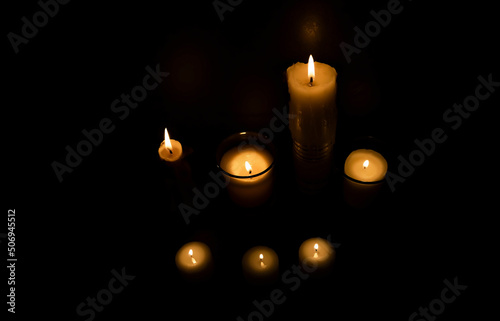 Candle flame, photo of different sized candles, on a dark background. Top view