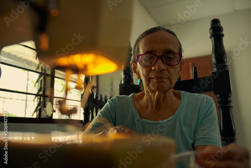 primerplano de mujer anciana colombiana cosiendo prenda de vestir en una maquina  photo