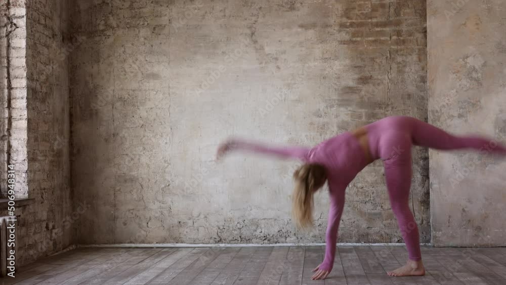 beautiful strong muscular woman doing stretching in gym. Healthy young adult woman in pink sportswear stretch alone. Fit thin gimnast doing acrobatics indoors, training on mat
