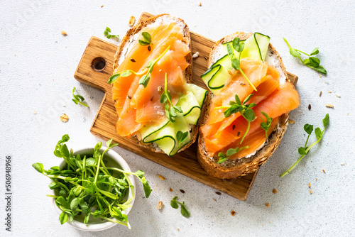 Open sandwich with cream cheese, salmon and cucumber. Top view at white table.