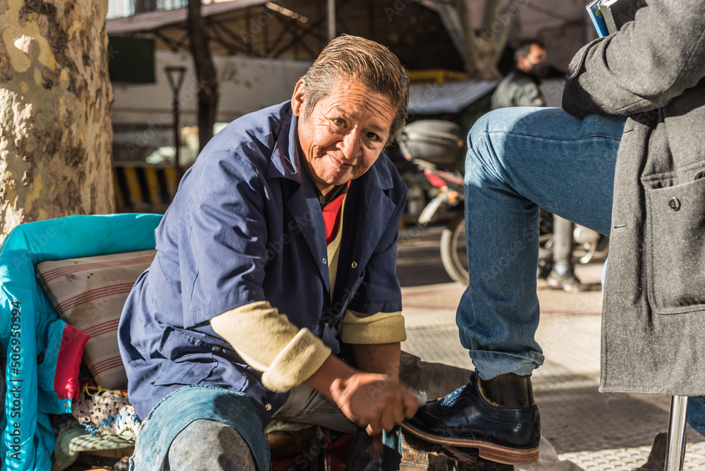 worker polishing a pair of black shoes on the street, a sunny day