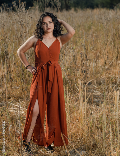 Pretty Latina posing in orange dress in an autumn field
