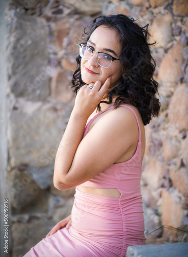 Pretty dark haired woman posing in short pink dress in urban eviroments