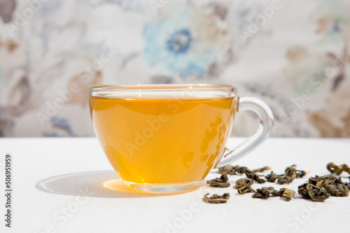 Hot cup of green tea with dry tealeaf on the table 