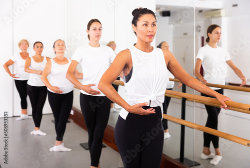 Asian girl in leotard training in ballet class with other dancers