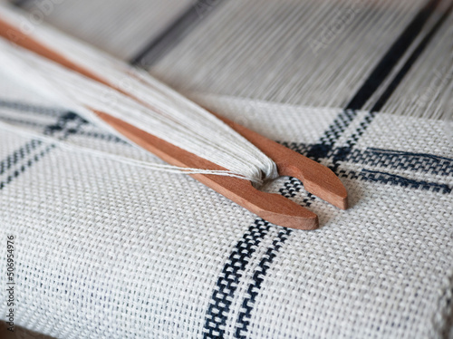 Black and white weaving project. Wooden shuttle with thread on the handloom