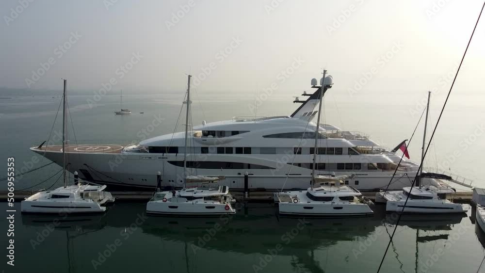Super yacht and sailing catamarans stand in a yacht marina on a foggy morning, drone view
