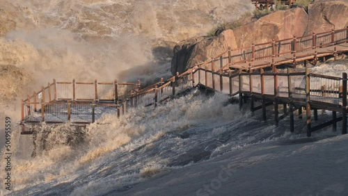 Water flows across viewing deck and walkway by Augrabies main waterfall, Orange River in flood