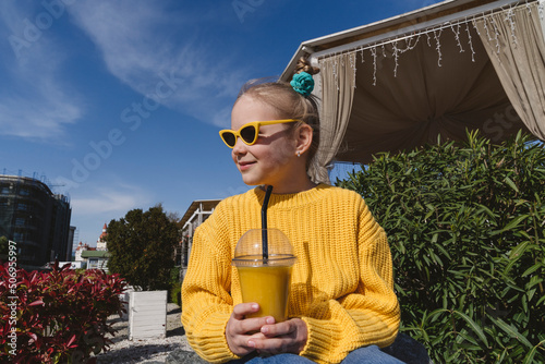 Portrait of a girl in a yellow sunglasses with a glass of fresh juice. photo