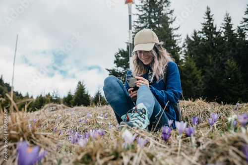 Mountain young girl looks at the phone and laughs in the nature photo