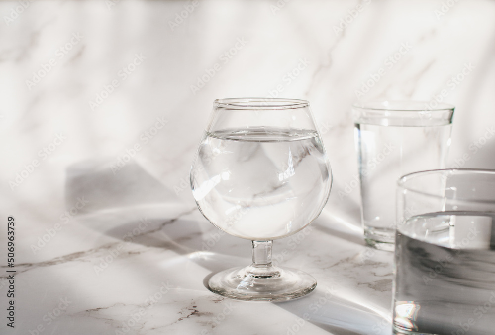 Fototapeta premium Sunlight through glass of water make light and shadow make a beautiful pattern by refraction of light on white background.