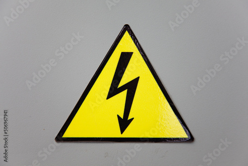 High voltage warning sign yellow triangle on grey industry wall