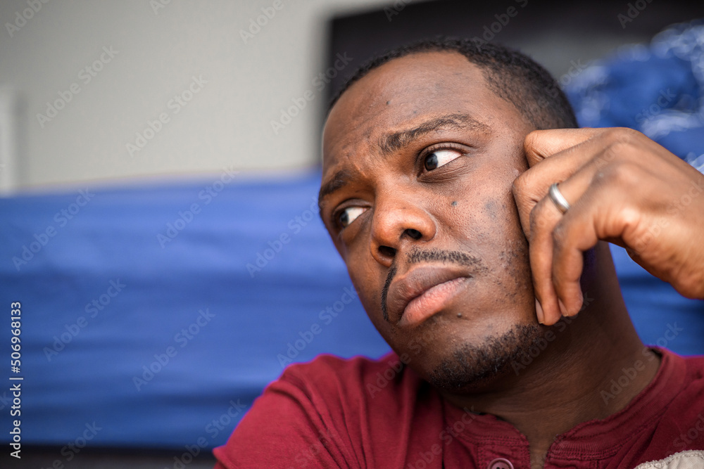 Fototapeta premium Depressed and anxious African American or black man sitting at home
