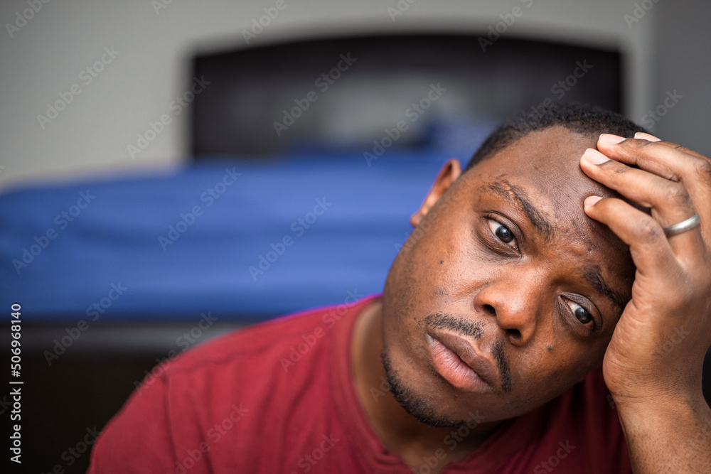 Fototapeta premium Depressed and anxious African American or black man sitting at home